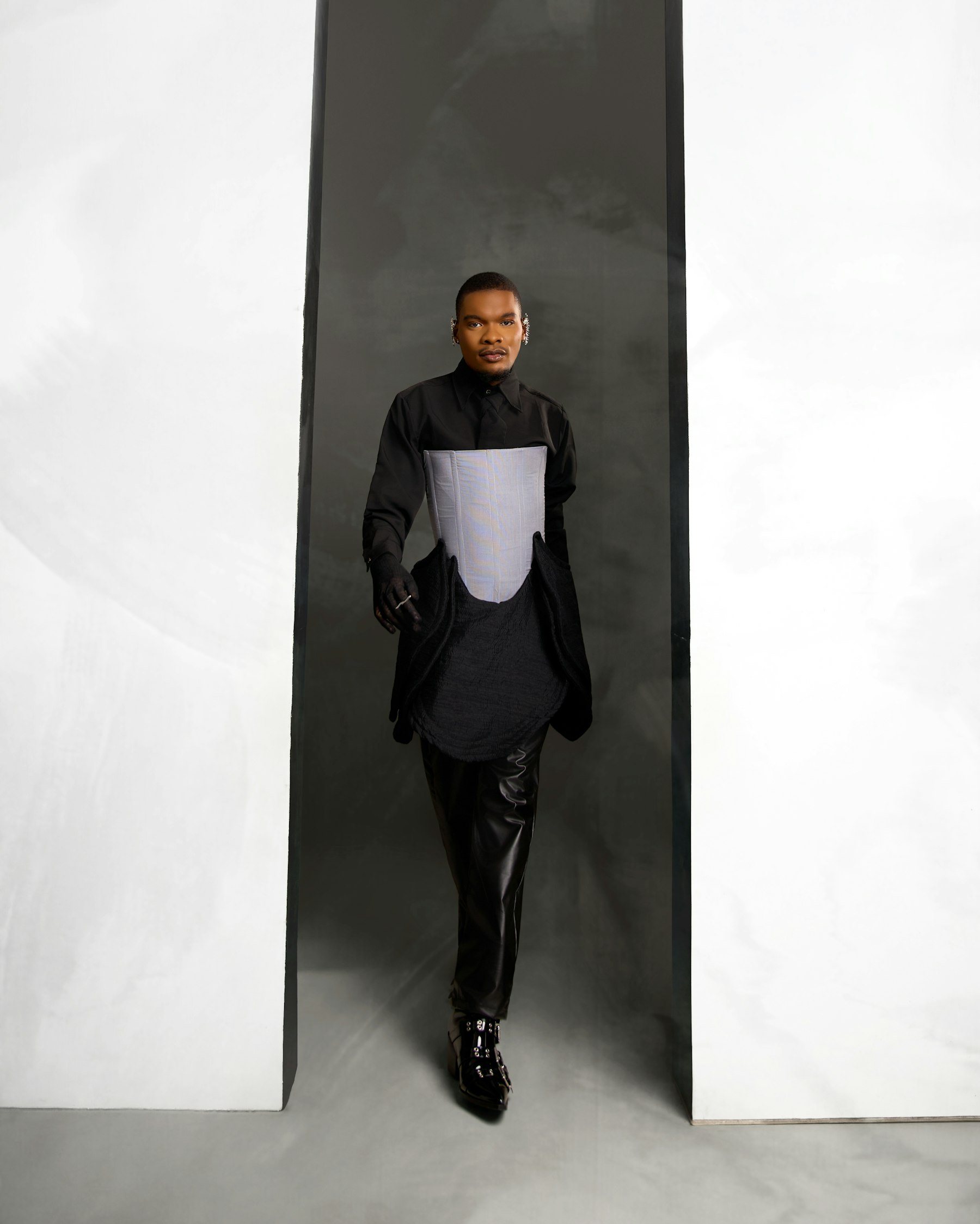 A man in dark clothes standing between two tall white panels.